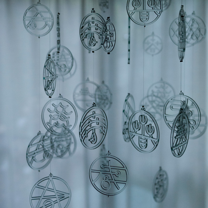 hanging mobile installation consisting of 64 NAMON (4 different sizes for each of 16 designs) tied by fishing line